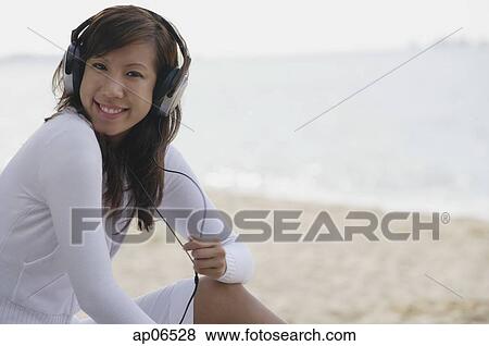 Young woman wearing headphones, smiling at camera View Large Photo Image Stock Photo - Young woman wearing headphones, smiling at camera. Fotosearch