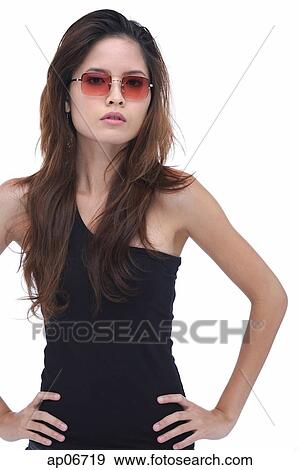 Stock Photo - Young woman wearing sunglasses, hands on hips. Fotosearch