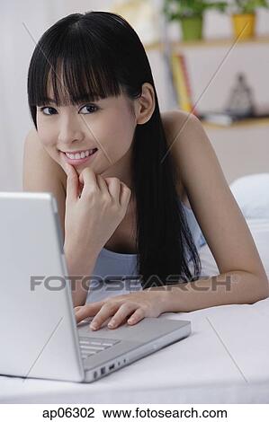 Young woman with laptop, hand on chin, smiling at camera View Large Photo Image Stock Image - Young woman with laptop, hand on chin, smiling at camera. Fotosearch