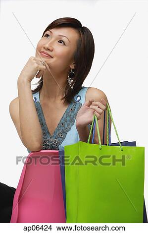 Young woman with shopping bags, looking away, hand on chin View Large Photo Image Picture - Young woman with shopping bags, looking away, hand on chin. Fotosearch