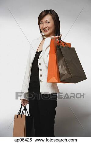 Young woman with shopping bags, smiling View Large Photo Image Stock Photography - Young woman with shopping bags, smiling. Fotosearch