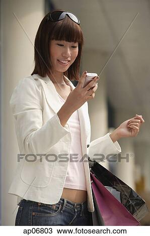 Young woman with shopping bags, using mobile phone View Large Photo Image Stock Image - Young woman with shopping bags, using mobile phone. Fotosearch