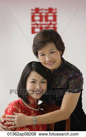 A bride and her mother hug and smile at the camera View Large Photo Image Stock Photo - A bride and her mother hug and smile at the camera. Fotosearch