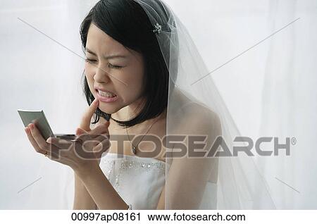 A bride checks her teeth in a mirror View Large Photo Image Stock Image - A bride checks her teeth in a mirror. Fotosearch
