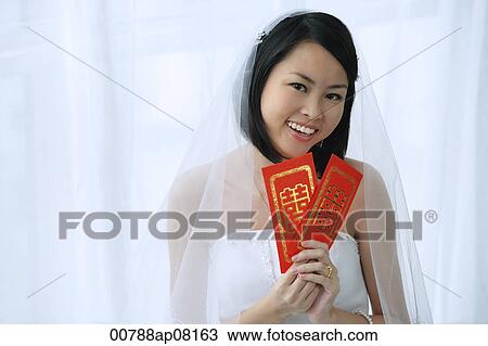 A bride smiles at the camera and holds out two red envelopes View Large Photo Image Stock Image - A bride smiles at the camera and holds out two red envelopes. Fotosearch