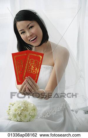 A bride smiles at the camera and holds out two red envelopes View Large Photo Image Stock Image - A bride smiles at the camera and holds out two red envelopes. Fotosearch