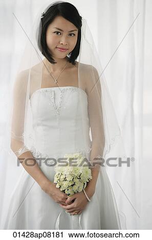 A bride with a bouquet of flowers looks at the camera View Large Photo Image Stock Image - A bride with a bouquet of flowers looks at the camera. Fotosearch