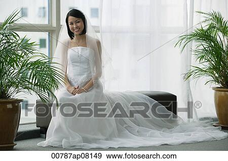 A bride with a white wedding gown sits down and smiles at the camera View Large Photo Image Stock Photo - A bride with a white wedding gown sits down and smiles at the camera. Fotosearch