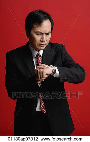 A businessman checks his watch for the time View Large Photo Image Stock Image - A businessman checks his watch for the time. Fotosearch