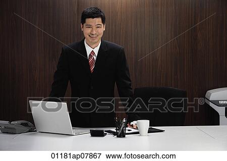 A businessman stands behind his desk View Large Photo Image Stock Photo - A businessman stands behind his desk. Fotosearch