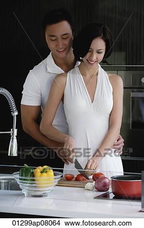 Picture - A couple prepare dinner together in the kitchen. Fotosearch