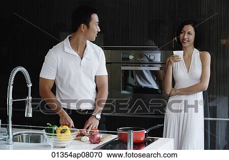 A couple prepare dinner together in the kitchen View Large Photo Image Stock Image - A couple prepare dinner together in the kitchen. Fotosearch