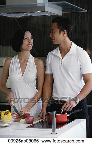 A couple prepare dinner together in the kitchen View Large Photo Image Stock Photograph - A couple prepare dinner together in the kitchen. Fotosearch