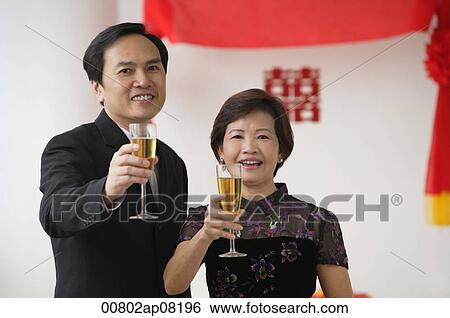 Stock Photograph - A couple raise their glasses for a toast. Fotosearch