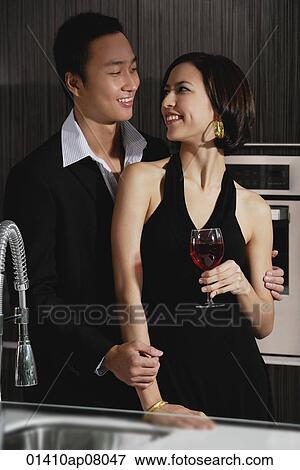 Stock Photo - A couple smile at each other while in the kitchen. Fotosearch