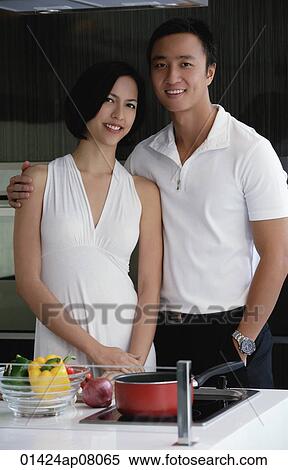 A couple smile at the camera as they stand in the kitchen View Large Photo Image Stock Photography - A couple smile at the camera as they stand in the kitchen. Fotosearch