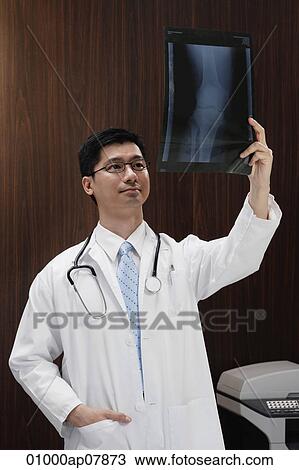A doctor holds up an x-ray View Large Photo Image Stock Image - A doctor holds up an x-ray. Fotosearch