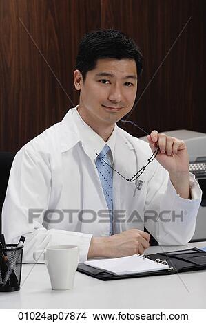 A doctor sits at his desk View Large Photo Image Picture - A doctor sits at his desk. Fotosearch
