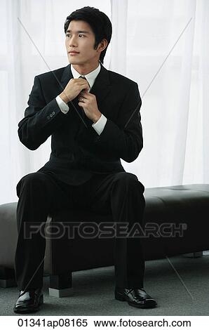 A groom adjusts his tie as he sits down View Large Photo Image Stock Photography - A groom adjusts his tie as he sits down. Fotosearch