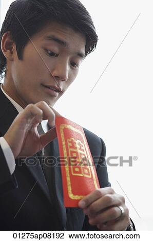 A groom looks inside a red envelope View Large Photo Image Stock Image - A groom looks inside a red envelope. Fotosearch