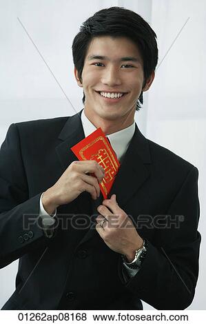 A groom smiles at the camera as he puts a red envelope in his pocket View Large Photo Image Stock Photo - A groom smiles at the camera as he puts a red envelope in his pocket. Fotosearch
