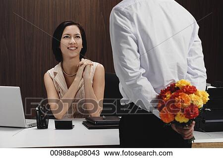 A man brings a woman flowers while she is at work View Large Photo Image Stock Image - A man brings a woman flowers while she is at work. Fotosearch