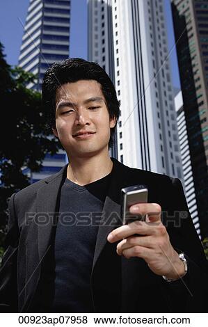 A man checks his phone while outdoors in the city View Large Photo Image Stock Photo - A man checks his phone while outdoors in the city. Fotosearch
