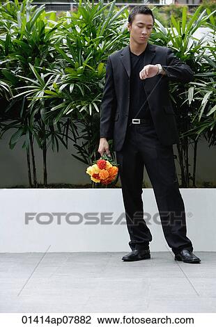 A man checks his watch while he holds a bunch of flowers View Large Photo Image Stock Image - A man checks his watch while he holds a bunch of flowers. Fotosearch