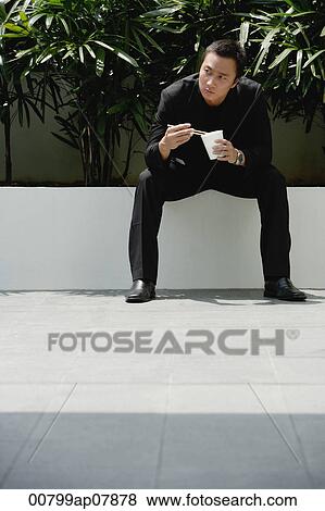 A man eats with chopsticks while outdoors View Large Photo Image Stock Photo - A man eats with chopsticks while outdoors. Fotosearch