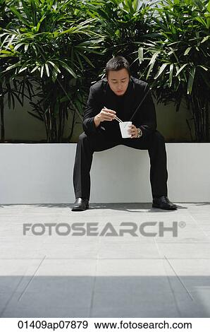 A man eats with chopsticks while outdoors View Large Photo Image Stock Photo - A man eats with chopsticks while outdoors. Fotosearch