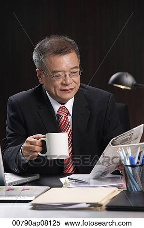 A man having a drink while working at his desk View Large Photo Image Stock Photography - A man having a drink while working at his desk. Fotosearch