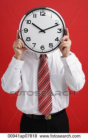 A man holds a clock in front of his face View Large Photo Image Stock Photo - A man holds a clock in front of his face. Fotosearch