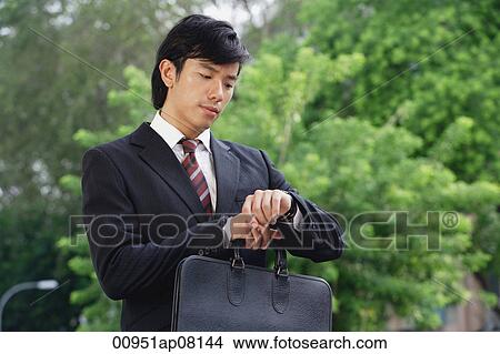 A man in a suit checks his watch for the time View Large Photo Image Picture - A man in a suit checks his watch for the time. Fotosearch