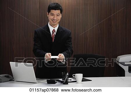 A man in a suit holds out his business card View Large Photo Image Stock Photo - A man in a suit holds out his business card. Fotosearch