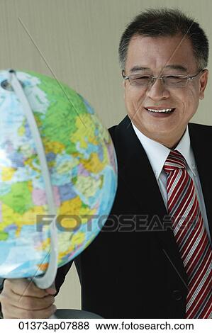 A man in suit holds a globe View Large Photo Image Stock Photo - A man in suit holds a globe. Fotosearch