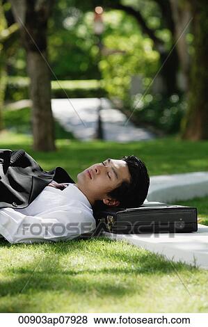 A man lies down and has a rest in the park View Large Photo Image Stock Photo - A man lies down and has a rest in the park. Fotosearch