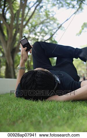 A man listens to music on a mp3 player in the park View Large Photo Image Stock Image - A man listens to music on a mp3 player in the park. Fotosearch