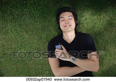A man listens to music on a mp3 player in the park View Large Photo Image Stock Image - A man listens to music on a mp3 player in the park. Fotosearch