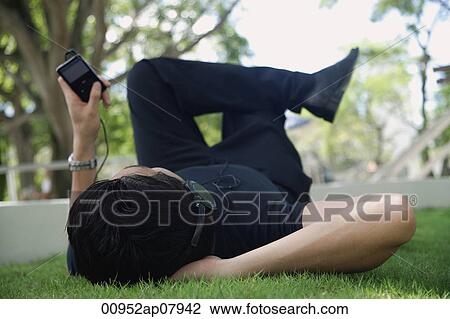 A man listens to music on a mp3 player in the park View Large Photo Image Stock Image - A man listens to music on a mp3 player in the park. Fotosearch