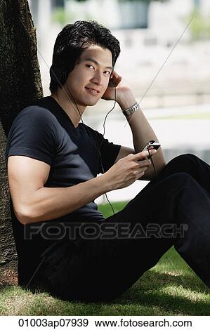 A man listens to music on a mp3 player in the park View Large Photo Image Stock Photo - A man listens to music on a mp3 player in the park. Fotosearch