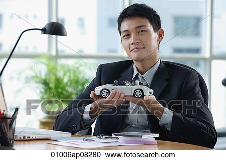 A man looks at the camera as he holds a toy car View Large Photo Image Stock Image - A man looks at the camera as he holds a toy car. Fotosearch