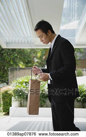 A man looks in a bag while outdoors View Large Photo Image Stock Photograph - A man looks in a bag while outdoors. Fotosearch