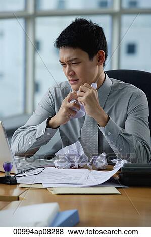 A man looks stressed as he works at his desk View Large Photo Image Stock Photo - A man looks stressed as he works at his desk. Fotosearch