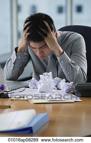 A man looks stressed as he works at his desk View Large Photo Image Stock Photo - A man looks stressed as he works at his desk. Fotosearch