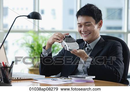 A man plays with a toy car on his desk View Large Photo Image Stock Photo - A man plays with a toy car on his desk. Fotosearch