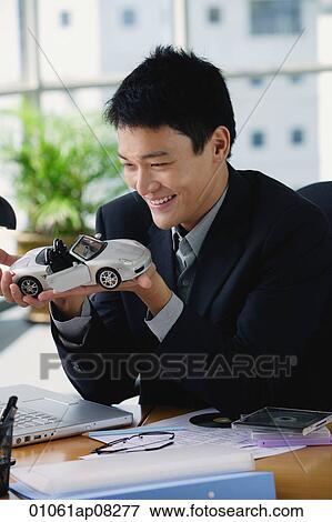A man plays with a toy car on his desk View Large Photo Image Stock Photo - A man plays with a toy car on his desk. Fotosearch