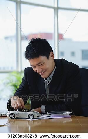 A man plays with a toy car on his desk View Large Photo Image Stock Photo - A man plays with a toy car on his desk. Fotosearch