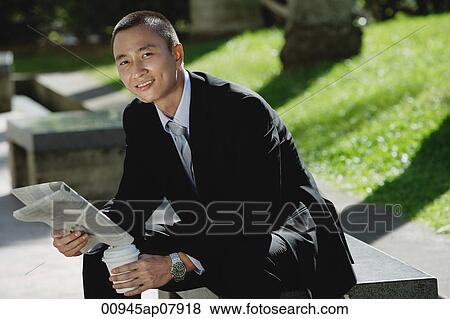 A man sits and reads the newspaper in the park View Large Photo Image Stock Photo - A man sits and reads the newspaper in the park. Fotosearch
