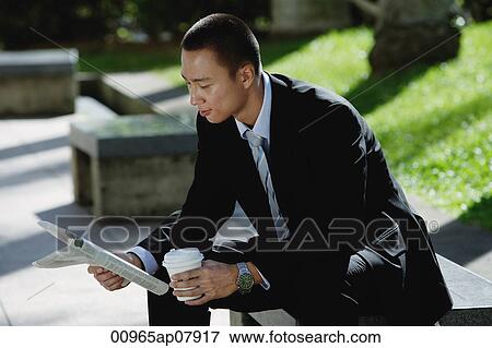 A man sits and reads the newspaper in the park View Large Photo Image Stock Photo - A man sits and reads the newspaper in the park. Fotosearch