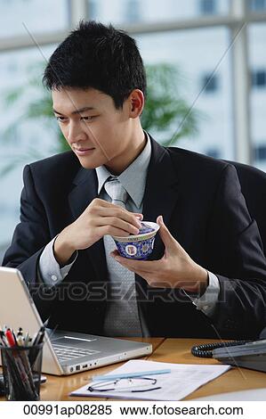 A man sits at his desk as he holds a Chinese tea cup View Large Photo Image Stock Photography - A man sits at his desk as he holds a Chinese tea cup. Fotosearch